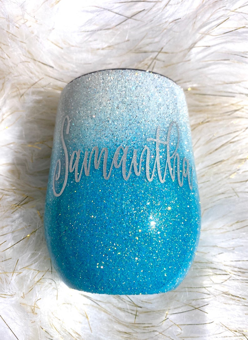May include: A blue and white ombre glitter tumbler with the name "Samantha" written in silver lettering.