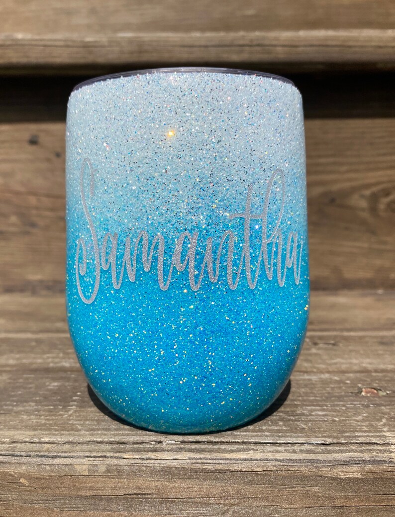 May include: A blue and white ombre glitter tumbler with the name "Samantha" written in white on the side.