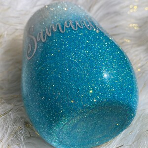 May include: A teal blue and white ombre glitter tumbler with the name "Savannah" written in white on the side.