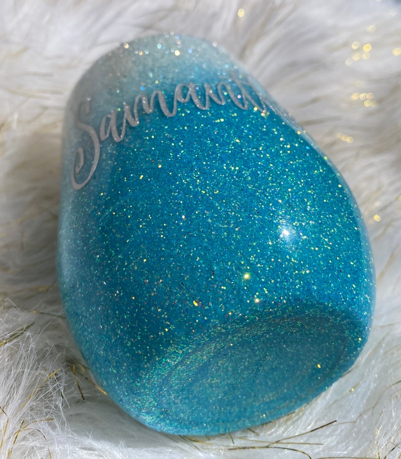 May include: A teal blue and white ombre glitter tumbler with the name "Savannah" written in white on the side.