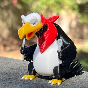 May include: A 3D-printed cartoon vulture figurine with a white head, yellow beak, and red neckerchief. The vulture holds two forks and has black wings and a white belly. Its feet are yellow with white claws.
