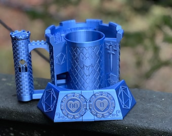 May include: A blue 3D printed castle-shaped dice tower with a heart-shaped dice tray. The tower has a small tower on the side and a sword design on the front. The dice tray has two heart-shaped compartments.