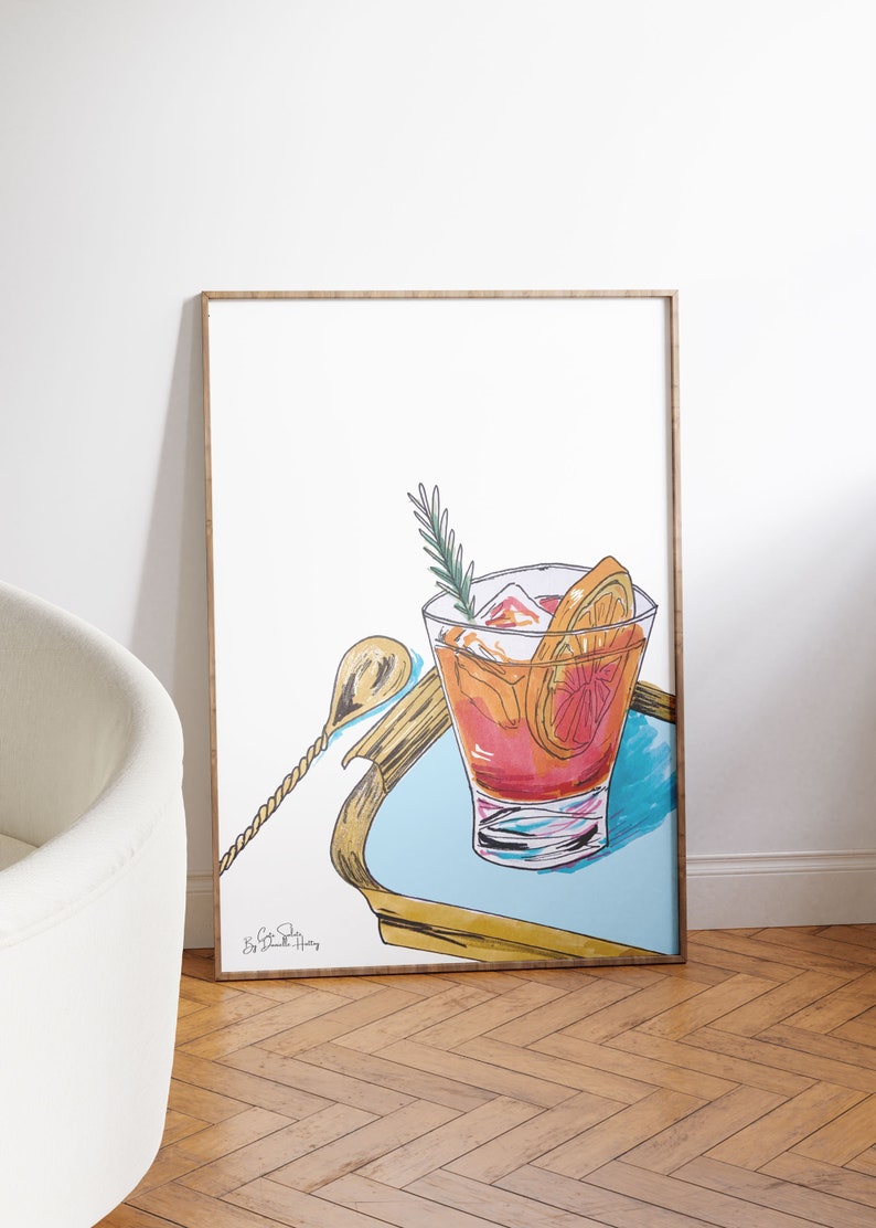 Puede incluir: Una ilustraci&oacute;n enmarcada de un c&oacute;ctel con una rodaja de naranja y una ramita de romero en una bandeja azul. El c&oacute;ctel est&aacute; en un vaso con hielo y una pajita. La ilustraci&oacute;n est&aacute; firmada "Big Cat Studio".