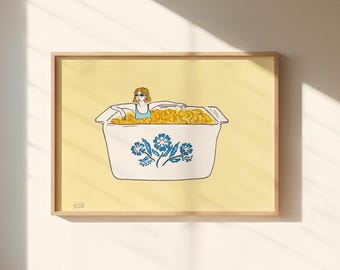 May include: A framed art print on a pale yellow background featuring a line drawing of a person wearing sunglasses sitting in a white rectangular casserole dish filled with yellow macaroni. The dish has a blue floral pattern on the front.