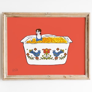 May include: A framed art print featuring a woman in sunglasses relaxing in a tub filled with golden macaroni and cheese. The white tub has a decorative blue bird and floral design against a red background.