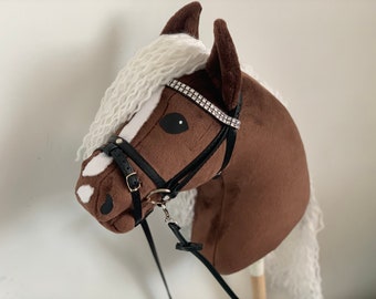 May include: Brown and white plush rocking horse with a black bridle and a rhinestone browband. The horse has a white mane and tail.