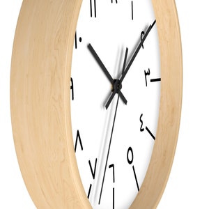 May include: A round, wooden wall clock with a white face and black hands. The numbers on the clock face are written in a stylized font.