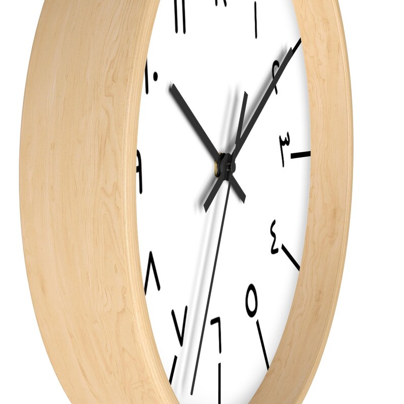 May include: A round, wooden wall clock with a white face and black hands. The numbers on the clock face are written in a stylized font.