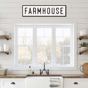 May include: A farmhouse kitchen with a white sink, wooden worktops, and open shelving. A black and white sign reading "FARMHOUSE" is above the window. The room is decorated with plants, dishes, and other kitchen essentials.