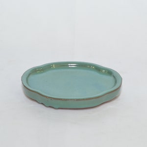 May include: A light green ceramic saucer with a scalloped edge.