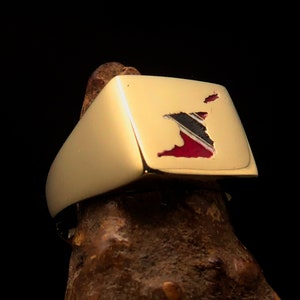 May include: A gold signet ring featuring an enamel inlay of the outline of Trinidad and Tobago in red, black and white.