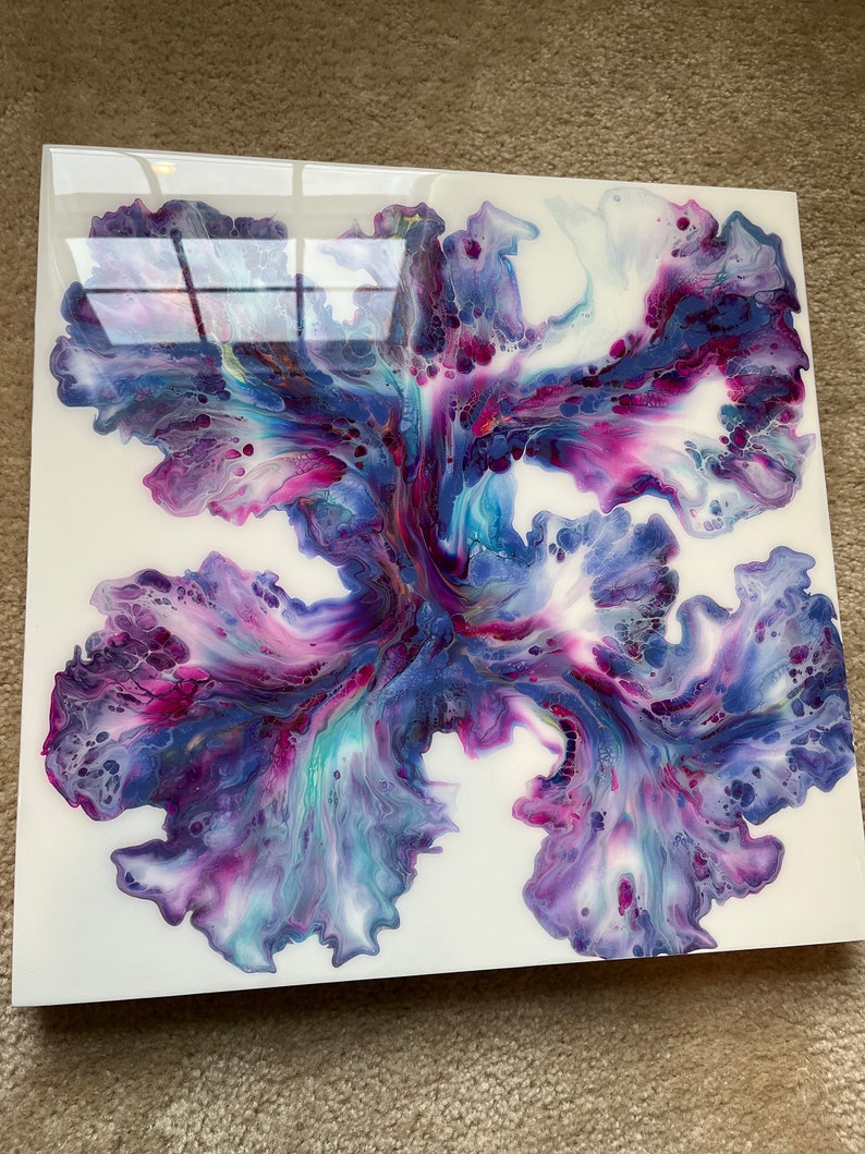 Puede incluir: Pintura abstracta sobre un lienzo blanco con un esquema de color morado, azul y blanco. La pintura se ha vertido y girado para crear un dise&ntilde;o &uacute;nico.