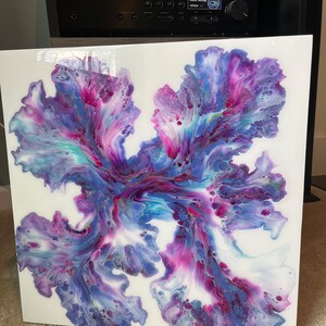 Puede incluir: Pintura abstracta sobre un lienzo blanco con colores que giran en p&uacute;rpura, rosa y azul. La pintura tiene un aspecto fluido y org&aacute;nico.
