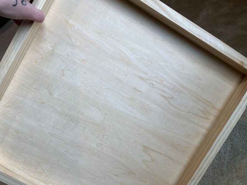 Puede incluir: Un marco de madera claro simple con una superficie de madera clara lisa. El marco est&aacute; hecho de madera sin terminar y tiene una forma rectangular simple.