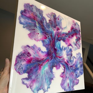 Puede incluir: Pintura abstracta sobre lienzo con colores p&uacute;rpura, azul y blanco que se arremolinan. La pintura tiene un dise&ntilde;o floral sobre un fondo blanco.