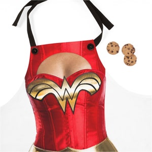 Pu&ograve; includere: Grembiule rosso e oro di Wonder Woman con un'apertura per il petto. Il grembiule ha bretelle nere e due bottoni neri.