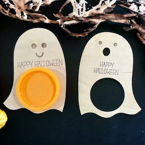 May include: Two wooden ghost-shaped Halloween treat holders. One has a small orange bowl and the other has a cut-out circle. Both have the text "Happy Halloween" written on them.