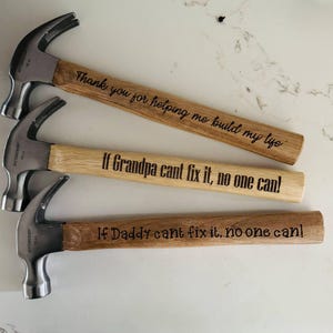 May include: Three wooden-handled hammers with metal heads. The handles are engraved with the text "Thank you for helping me build my life", "If Grandpa can't fix it, no one can!" and "If Daddy can't fix it, no one can!"