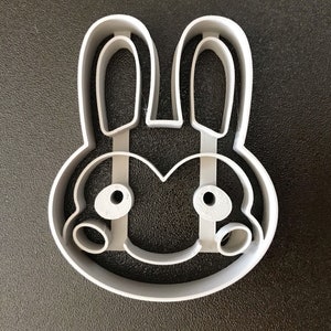 Puede incluir: Un cortador de galletas de pl&aacute;stico blanco con forma de conejo con orejas grandes y una cara simple.