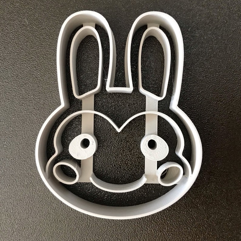 Puede incluir: Un cortador de galletas de pl&aacute;stico blanco con forma de conejo con orejas grandes y una cara simple.