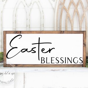 May include: A white wooden sign with a brown frame, featuring the text "Easter Blessings" in black cursive font.