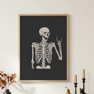 Cream-colored vintage-style illustration of a grinning skeleton raising one hand in a peace sign against a solid charcoal-black background.