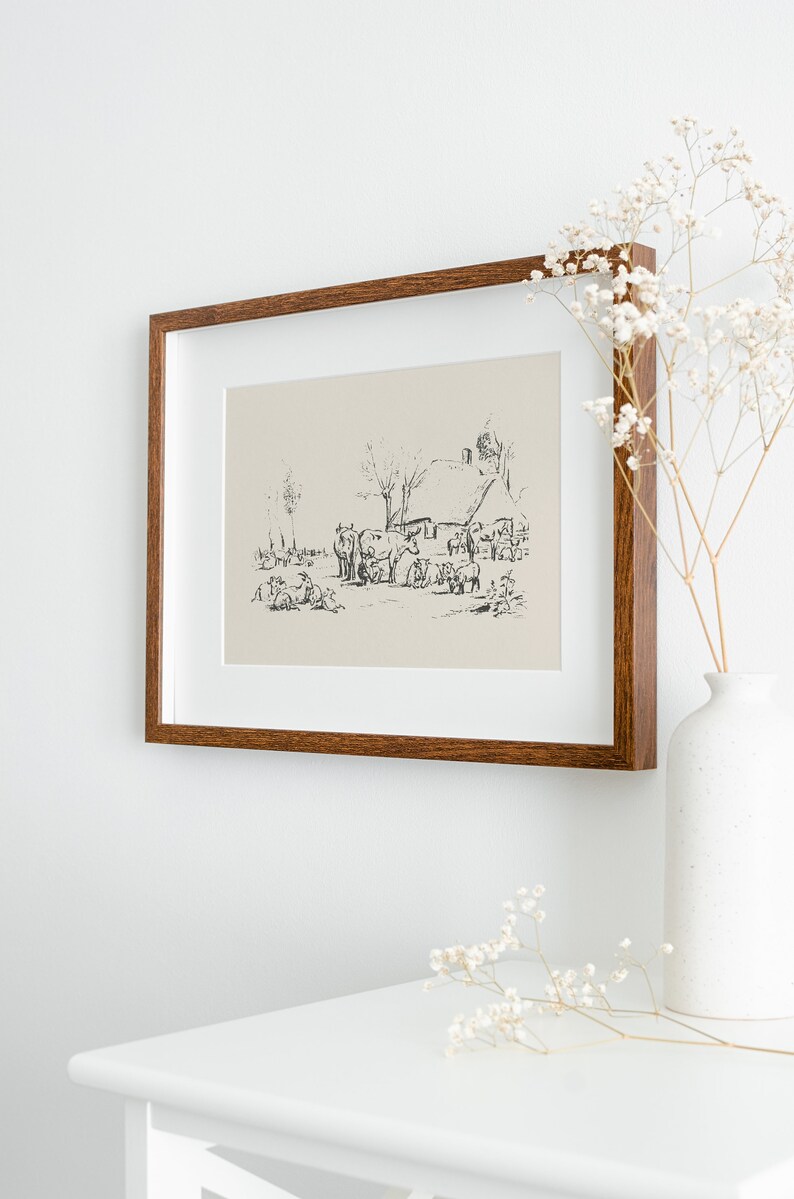 Pu&ograve; includere: Una stampa artistica incorniciata che presenta uno schizzo a inchiostro nero di una scena di fattoria rurale con bestiame e un cottage su uno sfondo beige chiaro. La cornice rettangolare &egrave; in legno marrone scuro con venature e bordo bianco.