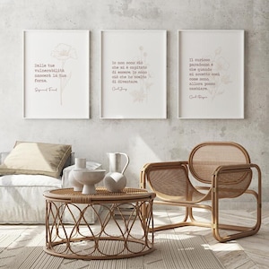 Puede incluir: Tres citas inspiradoras enmarcadas con acentos florales en una pared blanca. Las citas están en italiano y son de Sigmund Freud, Carl Jung y Carl Rogers. Las citas se muestran sobre una silla de mimbre y una mesa de café redonda de mimbre.