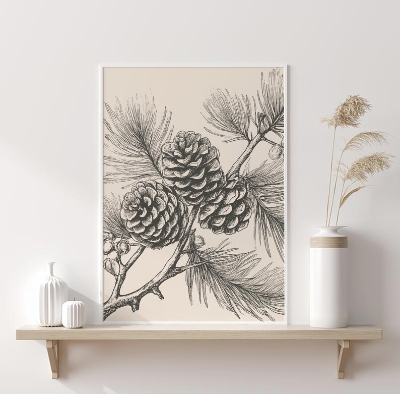 May include: Monochrome botanical print featuring detailed illustrations of pine cones and needles. The artwork is framed in white and displayed on a light-coloured shelf. A white vase with dried plants is on the shelf.