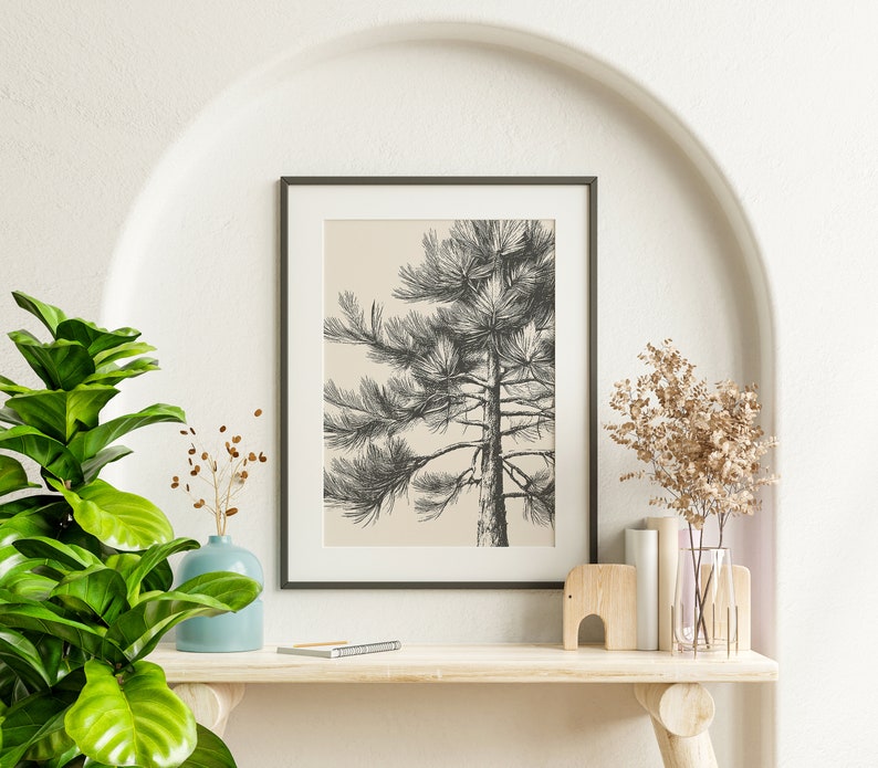 May include: A framed black and white illustration of a pine tree on a beige background, with a light blue vase, dried flowers, and a wooden elephant figurine on a wooden shelf.
