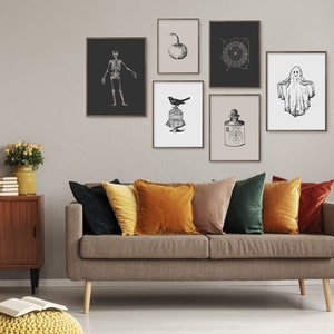 May include: A living room featuring a grey sofa with cushions in shades of green, orange and brown. The wall behind the sofa is adorned with black and white framed prints depicting a skeleton, a bird in a cage, a pumpkin, a spiderweb, a bottle of potion and a ghost.