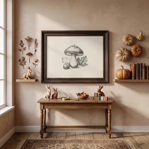 Pode incluir: Um desenho a carv&atilde;o emoldurado de um cogumelo, uma bolota e folhas centralizado numa parede. A divis&atilde;o apresenta uma mesa de consola em madeira, duas figuras de coelho, uma ta&ccedil;a de folhas secas, blocos de madeira e prateleiras com ab&oacute;boras.