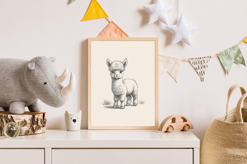 May include: A framed wall art print featuring a detailed black and white pencil sketch of a fluffy baby alpaca standing on grass. The artwork is enclosed in a light-colored wooden frame, showcasing the animal's textured fur and expressive face.
