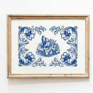 May include: A framed print of a blue and white illustration of a hen and chicks surrounded by floral designs.
