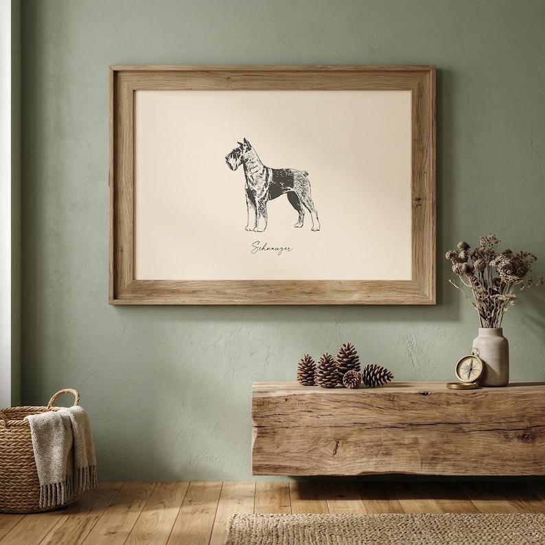 Schnauzer print in vintage ink sketch style on a warm cream background — a standing schnauzer with detailed crosshatch shading and a handwritten breed name below. Framed in rustic oak, displayed on a sage green wall above a live-edge wood console. Printable digital download for dog lovers, schnauzer owners, and pet-themed home decor.