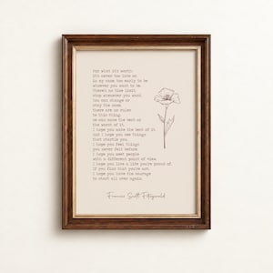 Può includere: Una stampa incorniciata che presenta il testo di una poesia di F. Scott Fitzgerald su uno sfondo color crema. Il testo è scritto in un carattere in stile macchina da scrivere, accompagnato da un semplice disegno al tratto di un fiore. La cornice è in legno marrone scuro.