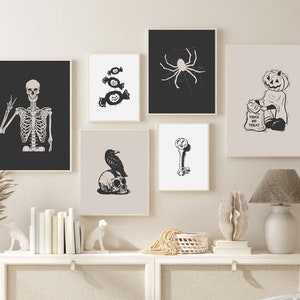 May include: A set of eight black and white Halloween-themed prints featuring a skeleton, candy, a spider, a pumpkin, a raven, a key, and a ghost. The prints are framed and arranged on a white wall.