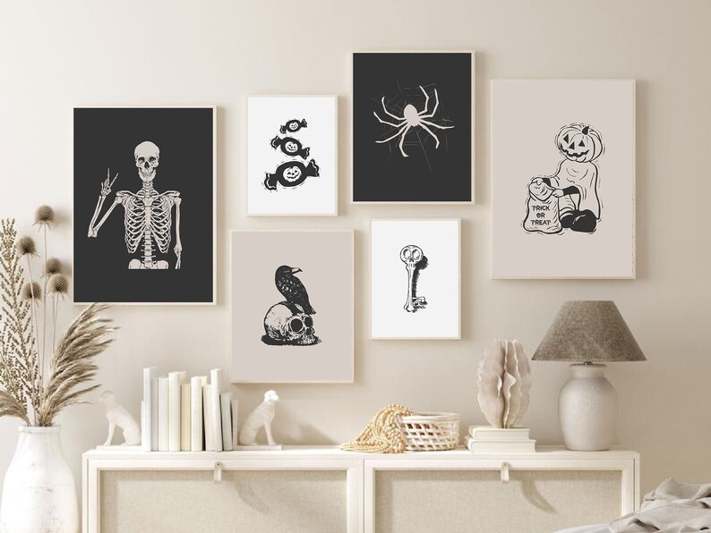 May include: A set of eight black and white Halloween-themed prints featuring a skeleton, candy, a spider, a pumpkin, a raven, a key, and a ghost. The prints are framed and arranged on a white wall.