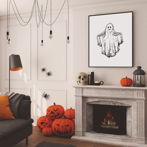 May include: A white living room decorated for Halloween with a fireplace, a couch, a black lamp, and a framed drawing of a ghost. There are orange pumpkins with carved faces and black spider decorations on the wall.