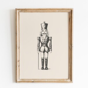 May include: A black and white illustration of a traditional nutcracker soldier in a vintage style frame.