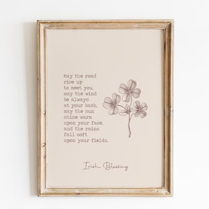 May include: Framed print featuring an Irish blessing with a floral illustration of a three-leaf clover. The text is in a serif font, and the artwork is in shades of brown and beige. The frame is a light, distressed wood.