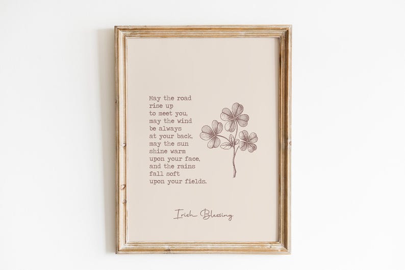 May include: Framed print featuring an Irish blessing with a floral illustration of a three-leaf clover. The text is in a serif font, and the artwork is in shades of brown and beige. The frame is a light, distressed wood.