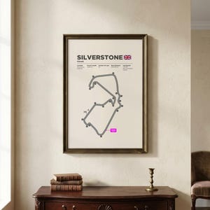 May include: A framed wall print featuring a technical diagram of the Silverstone Circuit in England. The poster displays the track layout in grey, the Union Jack flag, and text detailing location, circuit length, laps, and race distance.