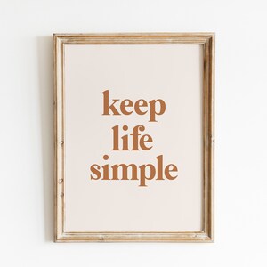 May include: A framed print with the text "keep life simple" in a brown font on a light beige background.