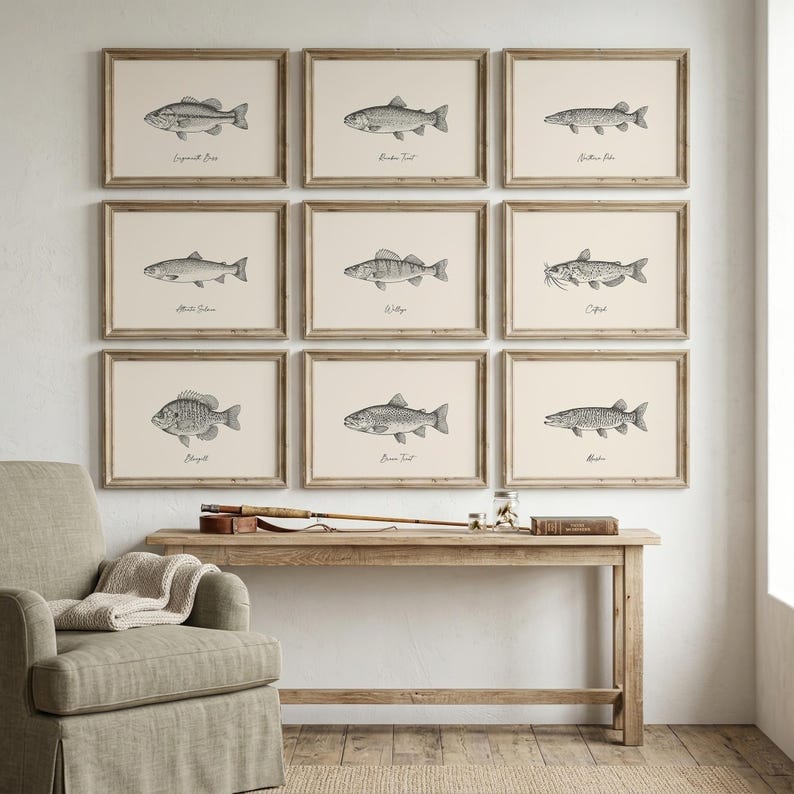 Vintage engraving-style freshwater fish wall art set featuring nine detailed pencil sketch illustrations — Largemouth Bass, Rainbow Trout, Northern Pike, Atlantic Salmon, Walleye, Catfish, Bluegill, Brown Trout, and Muskie — each in a separate light wood frame on a warm cream background, displayed as a gallery wall in a cozy farmhouse living room. Perfect as fishing wall art, lake house decor, or a fishing gift for him. Printable digital download available in multiple sizes.