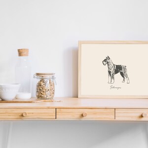 May include: A framed print featuring a black and white line drawing of a Schnauzer dog standing in profile. The artwork is set against a cream-colored background with the word Schnauzer written in cursive script beneath the dog illustration.