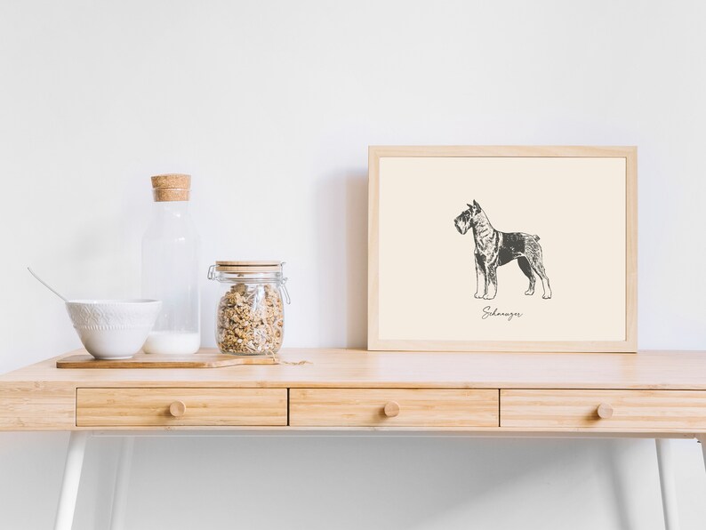 May include: A framed print featuring a black and white line drawing of a Schnauzer dog standing in profile. The artwork is set against a cream-colored background with the word Schnauzer written in cursive script beneath the dog illustration.