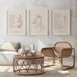 Set of three coordinating F Scott Fitzgerald quote prints in thin white frames arranged in a horizontal row on a concrete textured wall featuring She Was Beautiful botanical quote print, minimalist female figure line art and For What Its Worth botanical quote print, all in warm sepia tones on cream background, above a rattan coffee table with white ceramic vessels and a rattan lounge chair in a bright minimalist Scandi boho living room with linen bedding and herringbone wood floor
