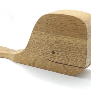 May include: A wooden whale sculpture with a carved smile. The whale is made of light brown wood with a natural grain pattern.