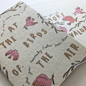 May include: A brown paper notebook with the text "The Birds of the Air" in gold lettering. The notebook features a pink bird illustration and a leafy branch with red berries.